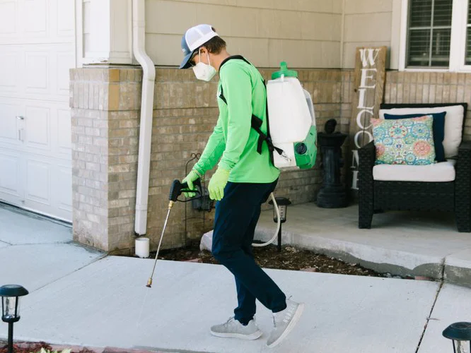 pest control technician spraying walkway